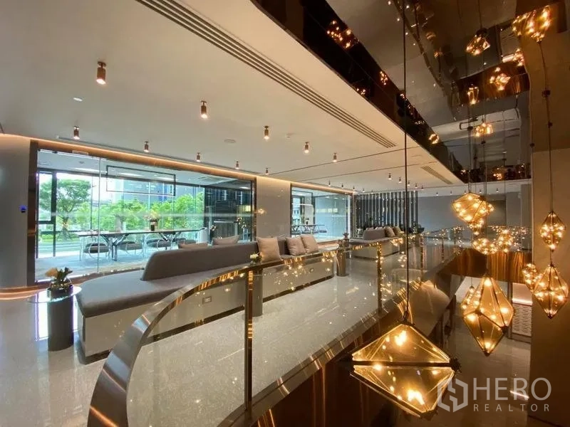 公寓 出售在Ratchathewi, Bangkok - 带装饰吊灯的共享休闲区，玻璃墙连接室外绿意。