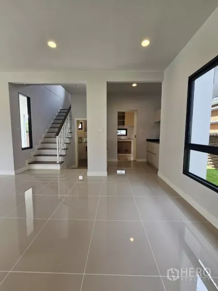 Detached House for sale in Lam Luk Ka, Pathum Thani - Living area leading to staircase and kitchen with large windows.
