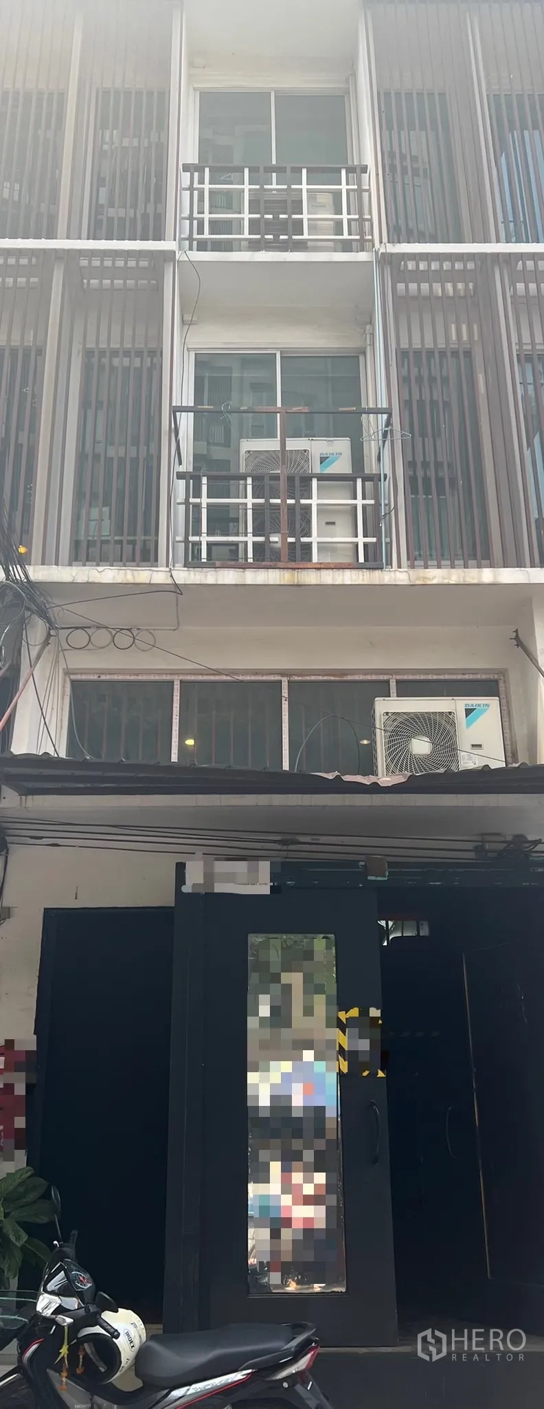 店屋 出租在Khlong Toei, Bangkok - 临街多层商铺房外立面，带阳台、推拉窗、竖向格栅及室外空调机组