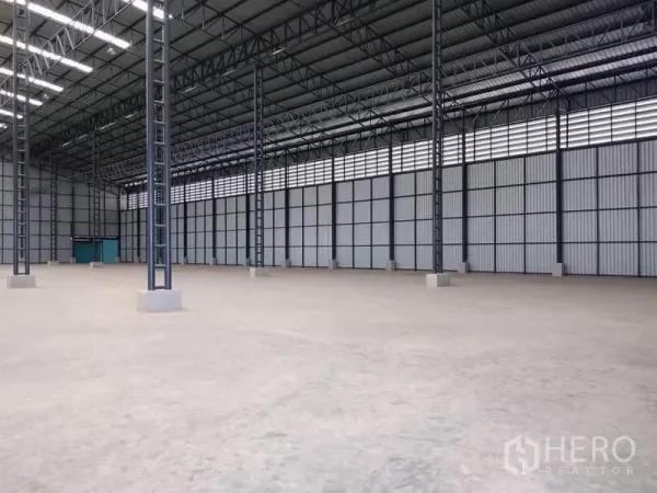 Factory for rent in Mueang Samut Prakan, Samut Prakan - Open production space with concrete floor, corrugated metal walls and teal service doors.