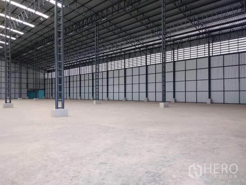 Factory for rent in Mueang Samut Prakan, Samut Prakan - Open production space with concrete floor, corrugated metal walls and teal service doors.