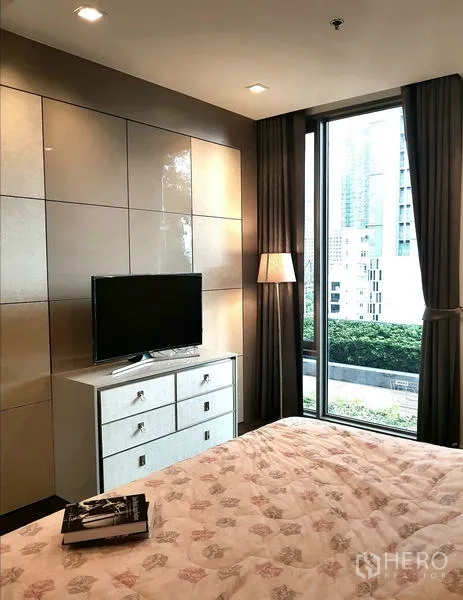 Condominium for rent in Sathon, Bangkok - Bedroom with window, TV on white chest and view of garden terrace.