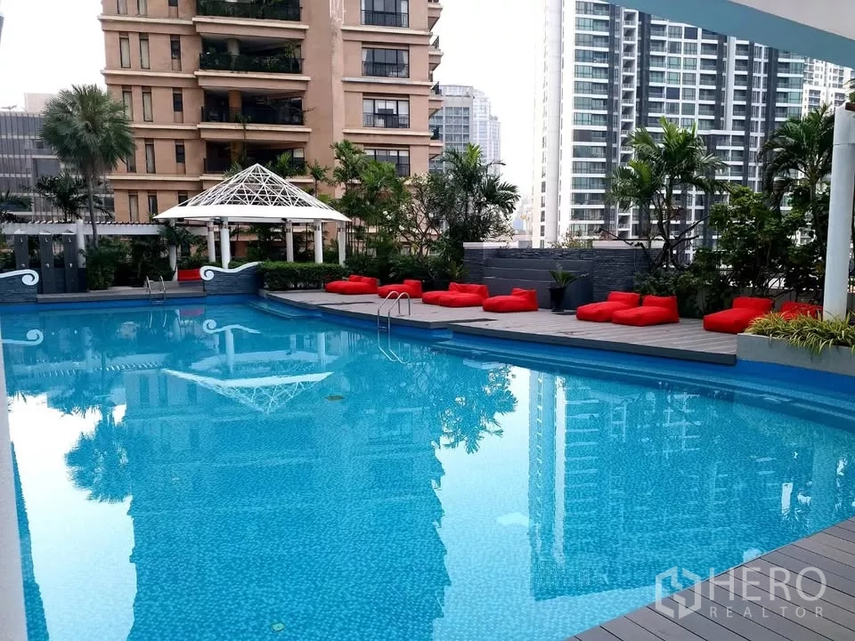 Condominium for rent in Khlong Toei, Bangkok - Outdoor swimming pool with deck seating, greenery, and skyline views in Phrom Phong.