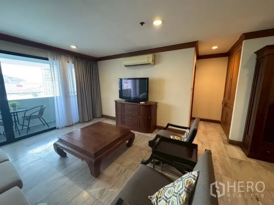 Condominium for rent in Watthana, Bangkok - Bright living room with TV console, sofa set, and sliding doors to a balcony with city views.