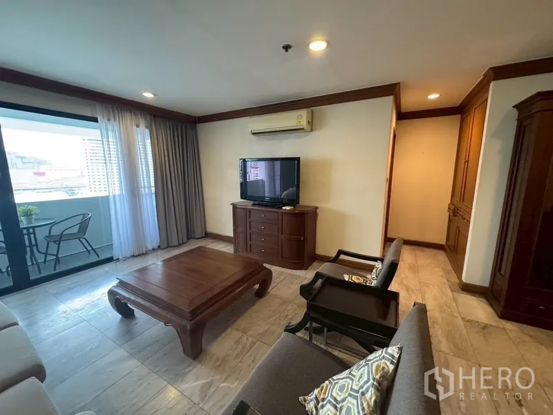 Condominium for rent in Watthana, Bangkok - Bright living room with TV console, sofa set, and sliding doors to a balcony with city views.