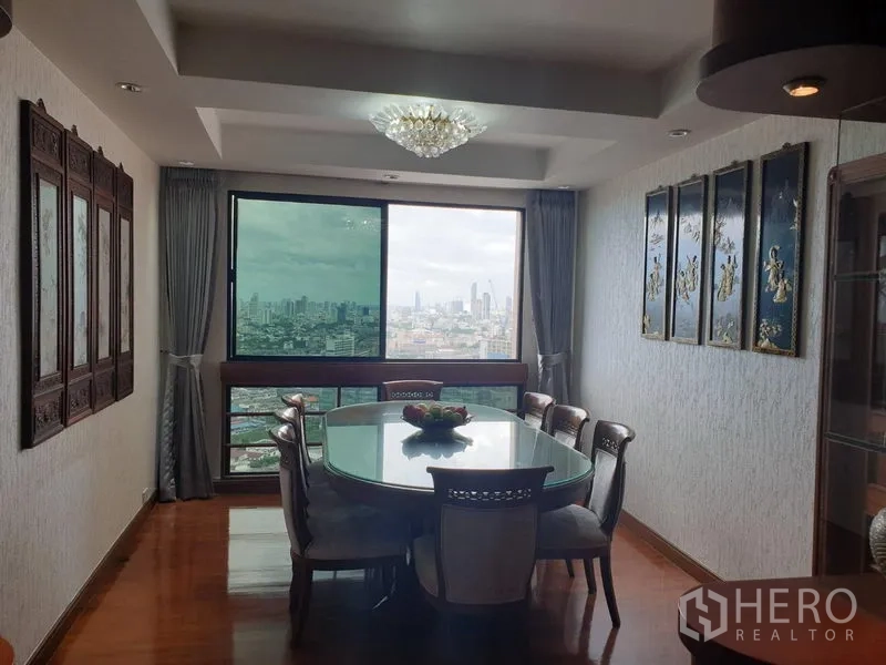 Condominium for rent in Khlong Toei, Bangkok - Dining room with chandelier, glass-top table and expansive city views through a picture window.