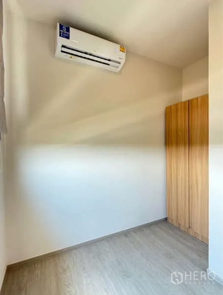 Townhouse for rent in Bang Phli, Samut Prakan - Small air-conditioned room with wooden wardrobe and light flooring.