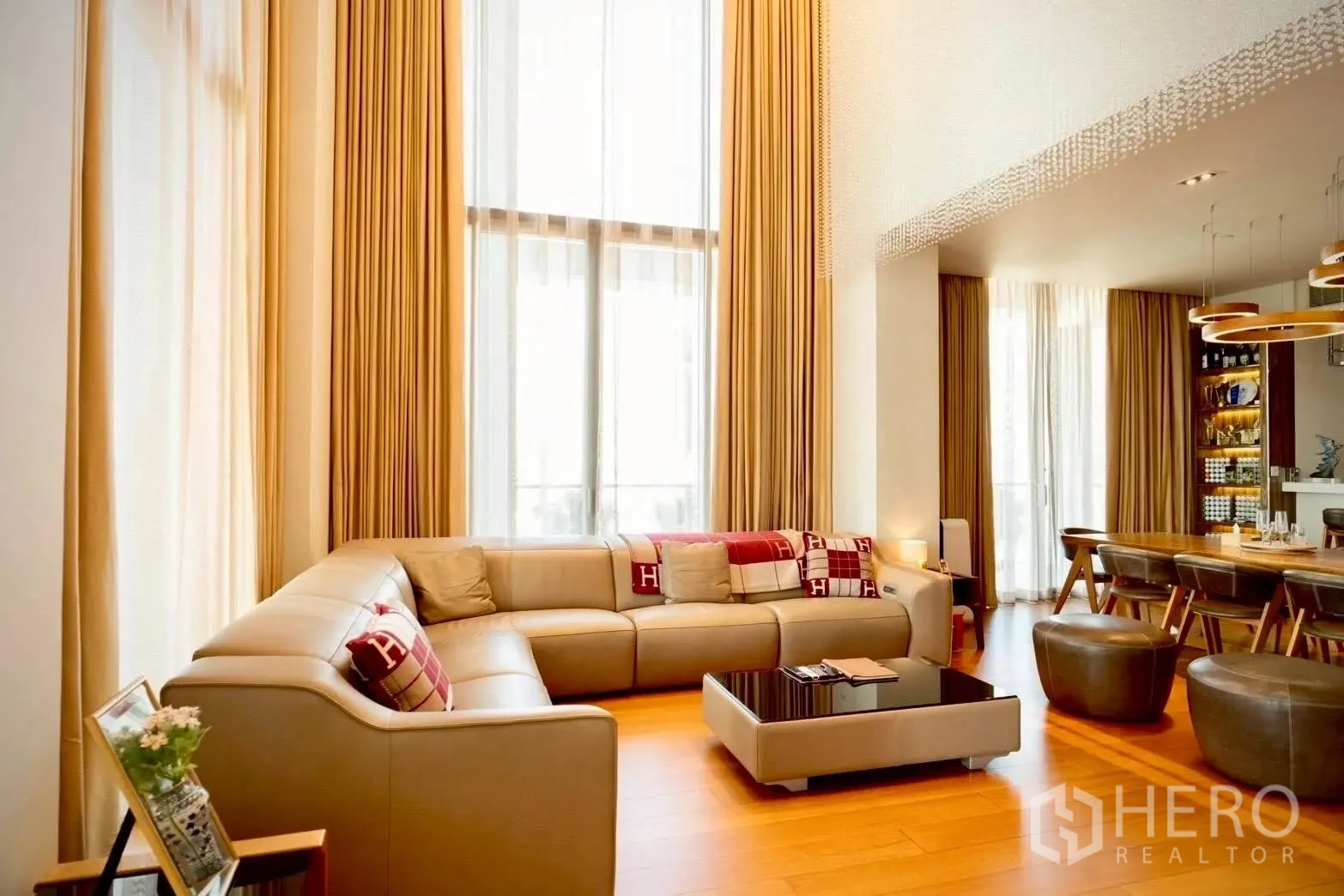 公寓 for sale in Sathon, Bangkok - 明亮客厅配高帘、转角沙发，旁连用餐区。