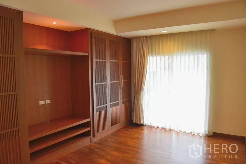 Apartment for rent in Sathon, Bangkok - Bedroom with full‑height wardrobes and curtain‑draped balcony door.