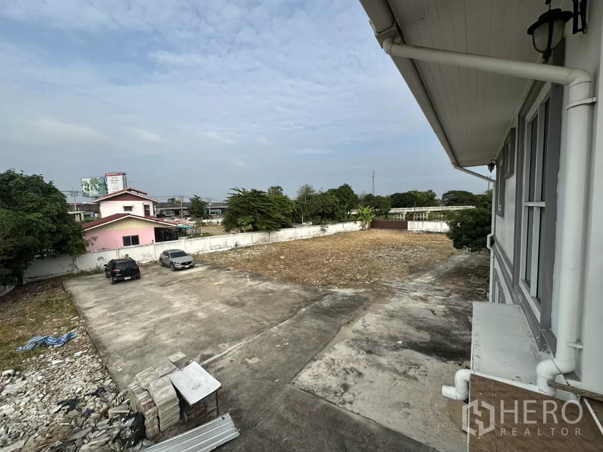 Home Office for rent - Upper-floor view over a concrete parking area with cars inside a walled compound.