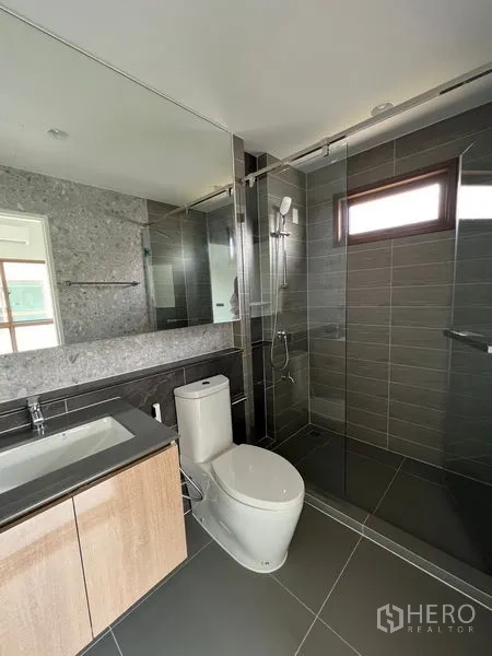 Detached House for rent in Bang Kapi, Bangkok - Modern bathroom with glass shower, stone counter, and grey tiles.
