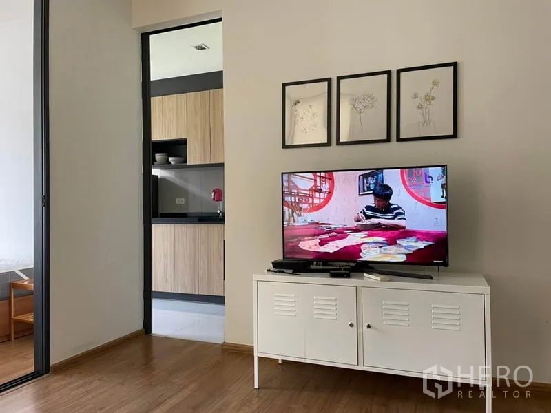 Condominium for sale in Watthana, Bangkok - TV console and framed artwork with a view toward the kitchen through the doorway.
