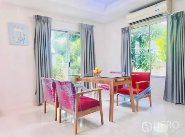 Detached House for rent or sale - Dining area with glass table and four red chairs, corner windows, gray drapes and split‑type air conditioner.