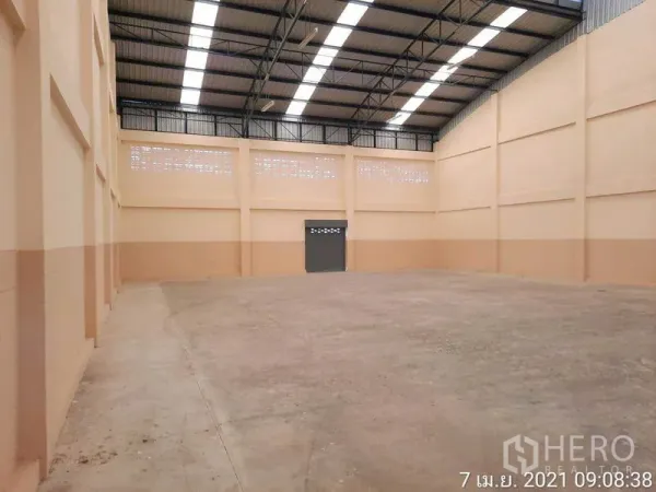 Factory for rent in Bang Bua Thong, Nonthaburi - Open factory floor with high ceiling, ventilation blocks and rear exit door.