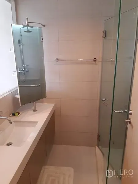 Condominium for rent in Khlong Toei, Bangkok - Clean bathroom featuring a glass-enclosed shower, long vanity and wall mirror.
