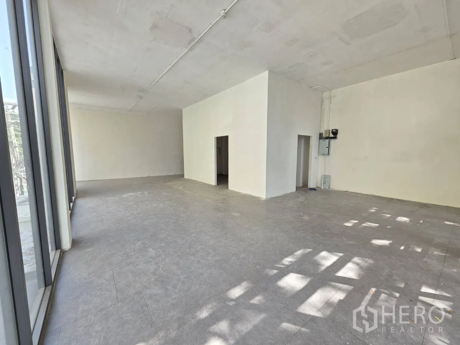 Retail Space for rent in Watthana, Bangkok - Large retail floor with tall windows, gray tile flooring, and a utility room.