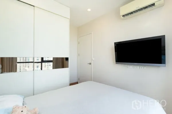 公寓 出租在Watthana, Bangkok - 卧室配推拉衣柜、壁挂电视与空调，瓦他那区公寓内景。