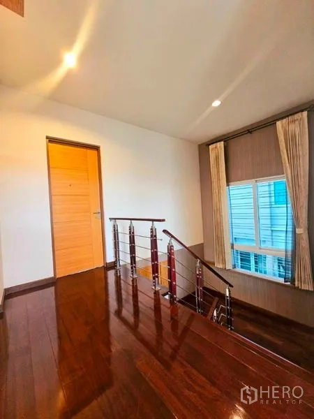 Detached House for rent in Chatuchak, Bangkok - Upper landing with polished wooden flooring, modern stair railing and a window.