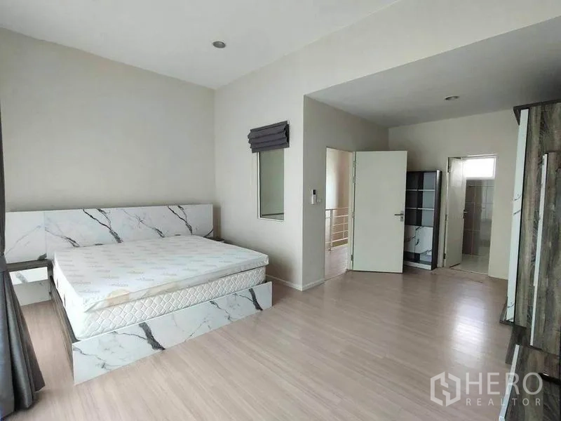 联排别墅 出租在Wang Thonglang, Bangkok - 主卧空间宽敞，仿大理石床架、浅色木地板，连接套内卫生间。