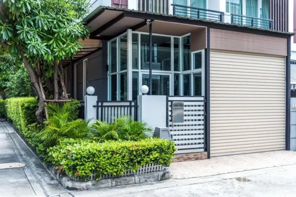 联排别墅 出售在Wang Thonglang, Bangkok - 现代联排别墅外观，转角落地窗、庭院绿篱与大门。