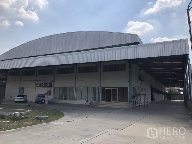 Factory for rent in Sai Noi, Nonthaburi - Front view of a standalone factory with a large covered loading bay and parking area in Sai Noi, Nonthaburi.