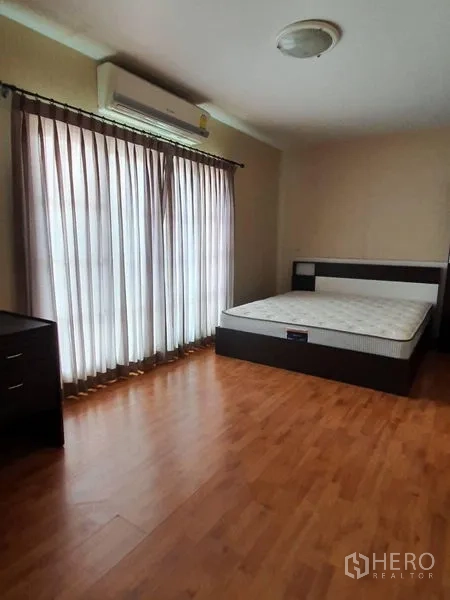 Townhouse for rent in Bueng Kum, Bangkok - Bedroom with sliding balcony doors, air conditioning, and a double bed on wood floors.