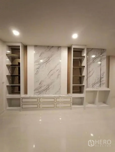บ้าน ให้เช่าหรือขายในPrawet, Bangkok - ผนังฟีเจอร์ลายหินอ่อนพร้อมชั้นวางและตู้ล่างในห้องนั่งเล่น