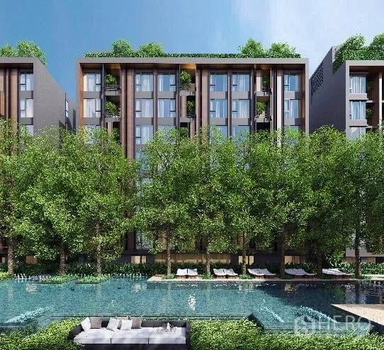 Condominium for rent in Khlong Toei, Bangkok - Low-rise condominium facade framed by trees with a large swimming pool and sun loungers.