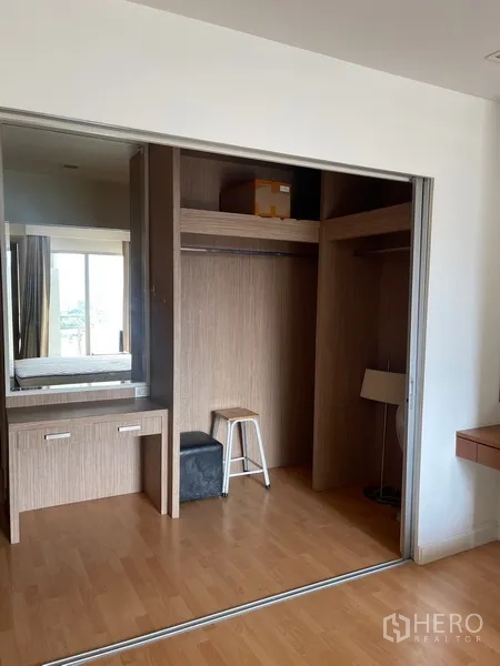 Condominium for rent in Khlong Luang, Pathum Thani - Large wardrobe niche with sliding doors, upper storage, and a small vanity desk.
