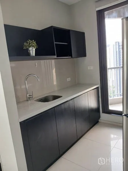 Condominium for rent - Minimalist pantry with sink and dark cabinetry, door opening to a small service balcony.