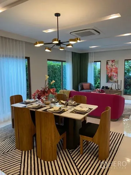 Detached House for sale in Bang Kapi, Bangkok - Open-plan dining and living area with modern chandelier, floor-to-ceiling windows and garden views.