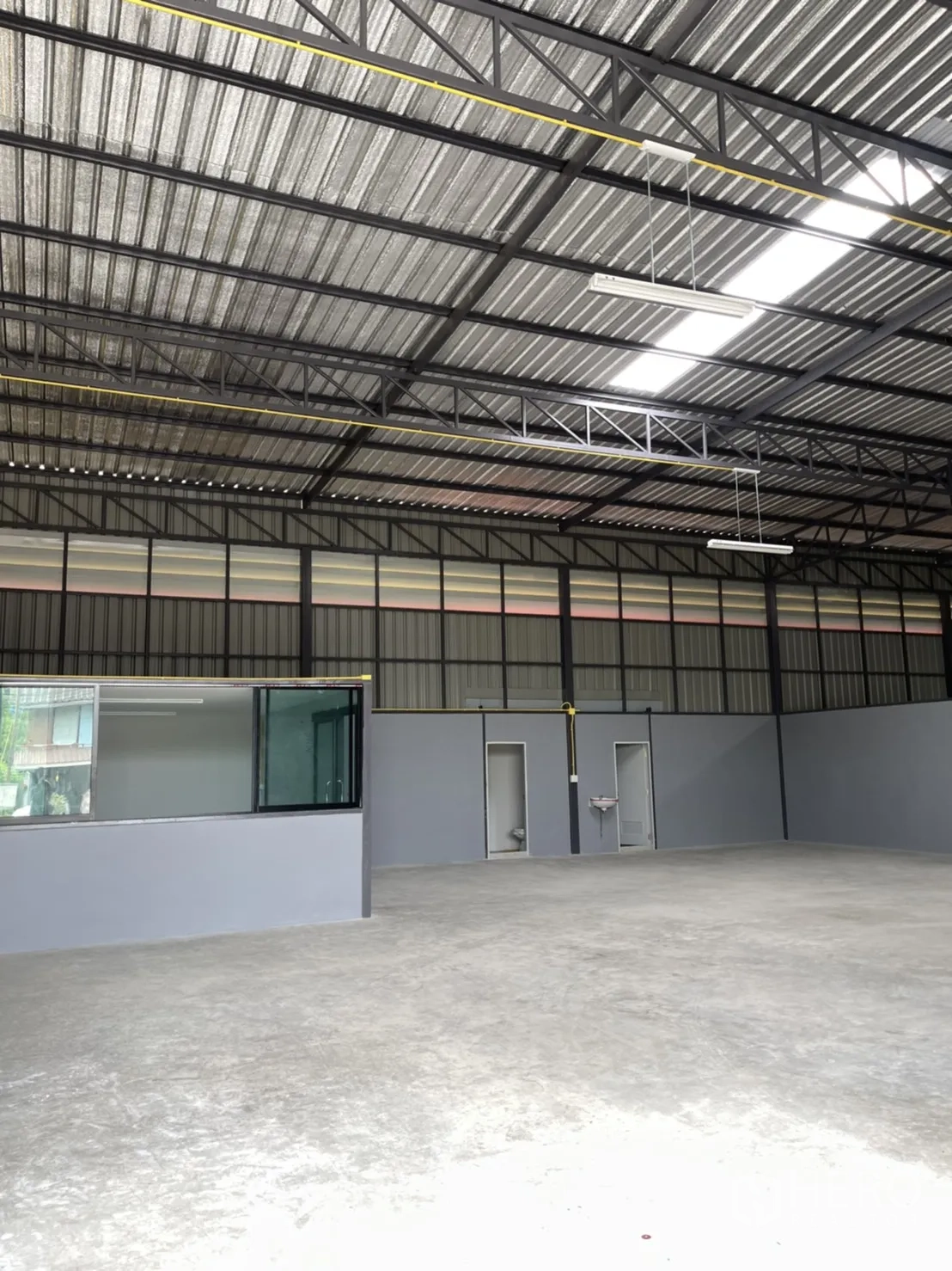Factory for rent in Khlong Luang, Pathum Thani - Close view of metal truss roof with LED lighting above the office section and restroom doors.