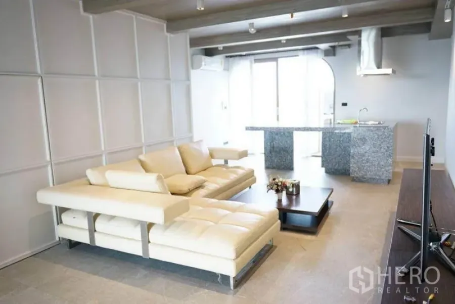 Condominium for rent or sale in Bang Na, Bangkok - Another view of the open‑plan living area with white sectional sofa and granite island.