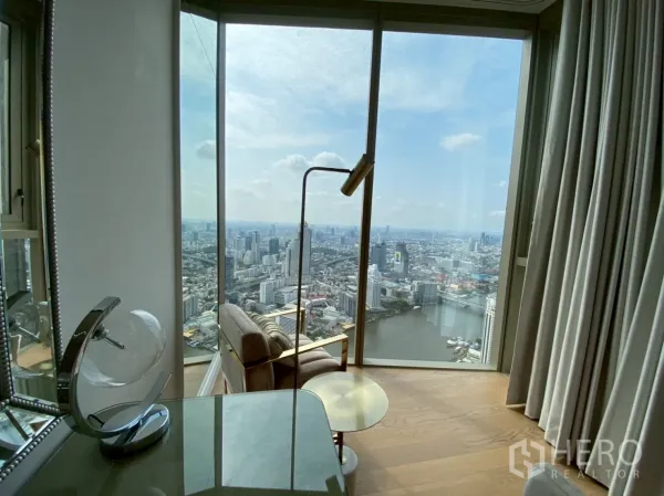 公寓 出租在Khlong San, Bangkok - 落地窗旁阅读椅，尽览河景与城市全景。