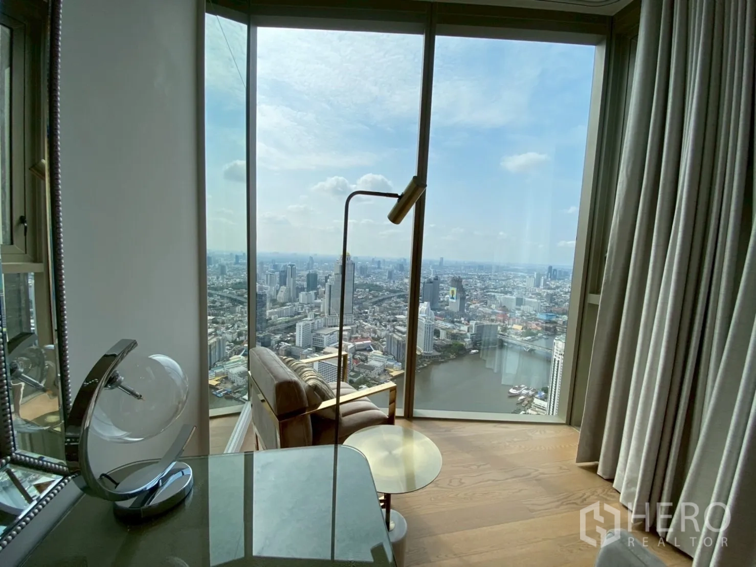 公寓 出租在Khlong San, Bangkok - 落地窗旁阅读椅，尽览河景与城市全景。