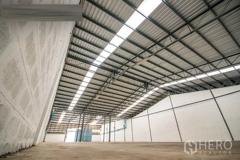 Warehouse for rent - Low-angle view of insulated metal roof and bright ventilation panels along the walls.