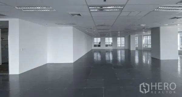 สำนักงาน ให้เช่า - พื้นที่ชั้นสำนักงานกว้างพร้อมเสา ผนังสีขาว เพดานแขวนไฟ และหน้าต่างหลายบานรับแสงธรรมชาติ