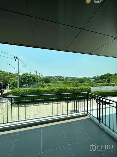 独立式住宅 出售在Prawet, Bangkok - 阳台金属栏杆，眺望绿地与静谧街景。