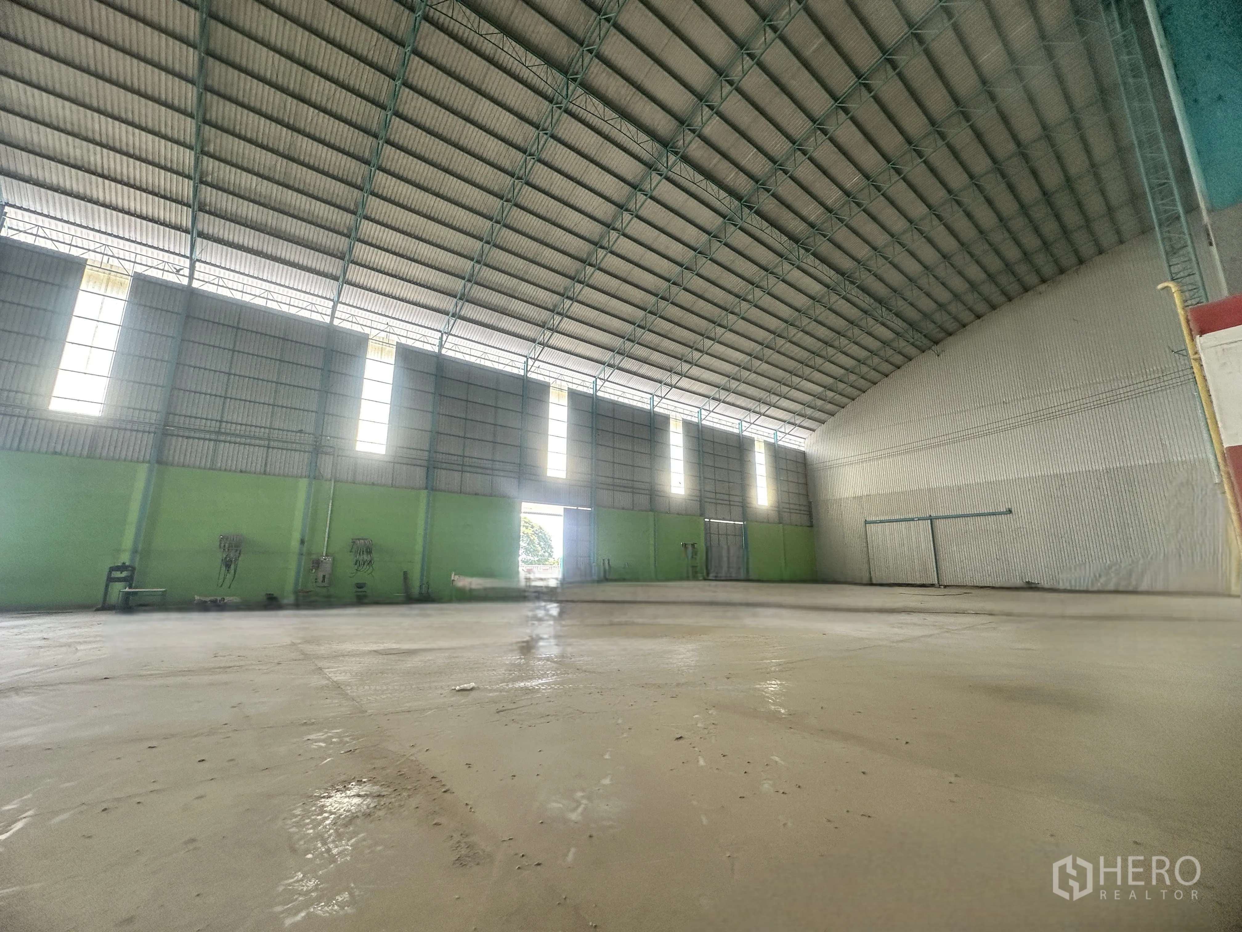 Warehouse for rent in Sai Noi, Nonthaburi - Warehouse hall with high roof, polished concrete slab, and multiple large entry doors.