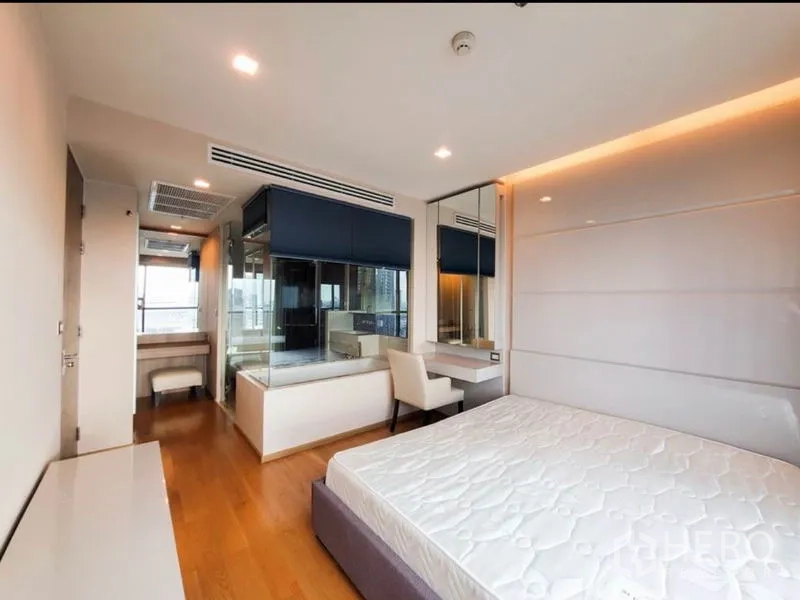 Condominium for rent in Bang Rak, Bangkok - Master bedroom with glass-walled ensuite bathroom and vanity desk.