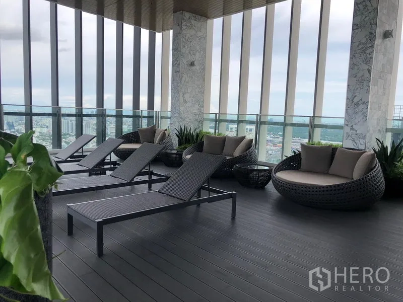 公寓 出租在Khlong Toei, Bangkok - 空中休闲露台，配躺椅与圆形沙发，享城市全景。