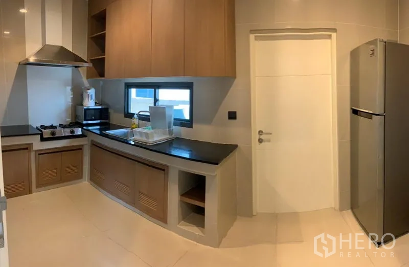 Detached House for rent or sale in Bang Kapi, Bangkok - Modern separate kitchen with gas hob, range hood, built-in cabinets and stainless refrigerator.