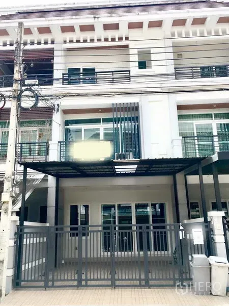 Townhouse for rent in Prawet, Bangkok - A three-storey townhouse exterior in Prawet with a gated carport and balconies.