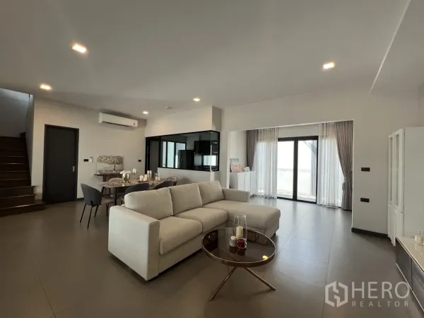 Detached House for rent in Bang Phli, Samut Prakan - Open-plan living room with L-shaped sofa, dining set and sliding glass doors.