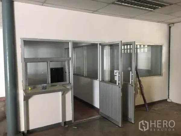 Warehouse for rent in Prawet, Bangkok - Ground-floor partitioned office rooms with glass windows and metal doors inside the warehouse.