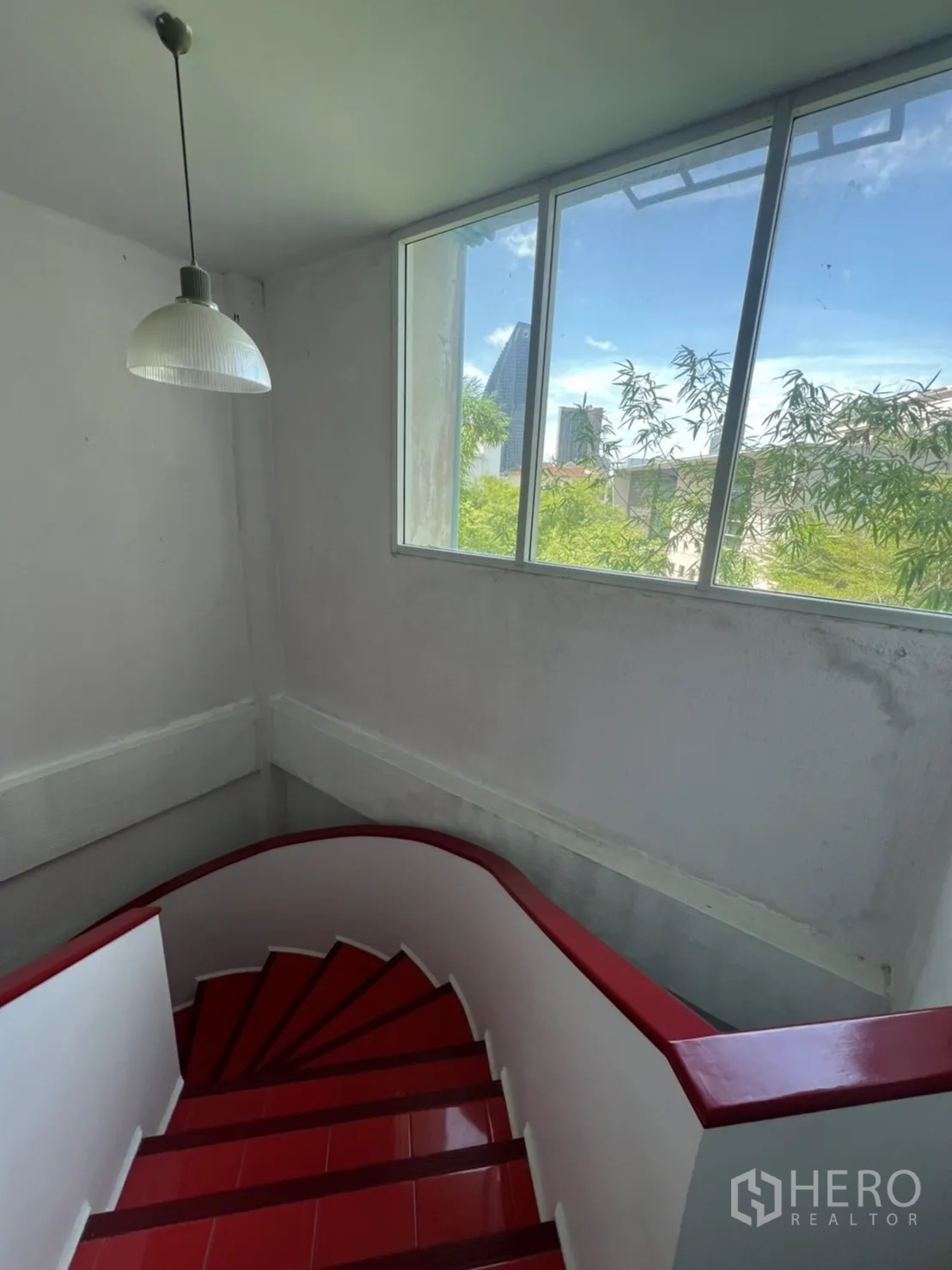 Shophouse for rent in Khlong Toei, Bangkok - Stairwell window bringing natural daylight with views of greenery and city skyline.