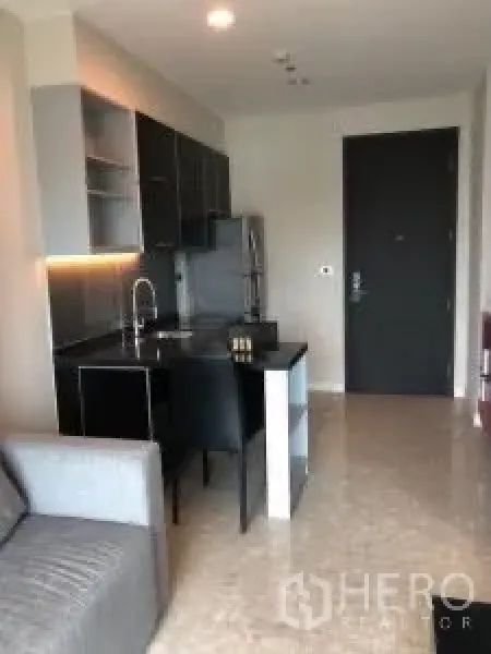 Condominium for rent or sale in Khlong Toei, Bangkok - Compact kitchen with black cabinetry, dining island and entrance door.