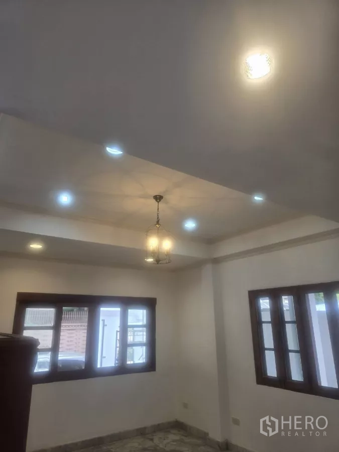 Detached House for rent in Phra Khanong, Bangkok - Cozy ground-floor room with recessed lighting, chandelier and surrounding windows.