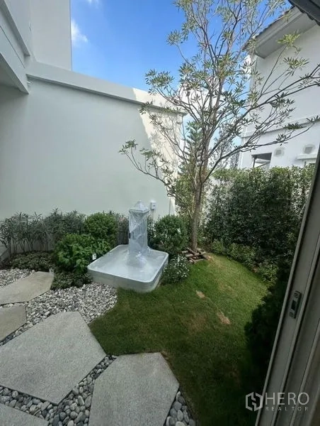 Detached House for rent - Pocket garden with a tree, shrubs, stepping stones, and a small fountain base.