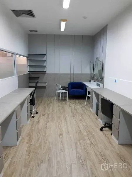 办公空间 出租在Khlong Toei, Bangkok - 狭长工作间，内置长桌、镜面、搁架和蓝色单人沙发。